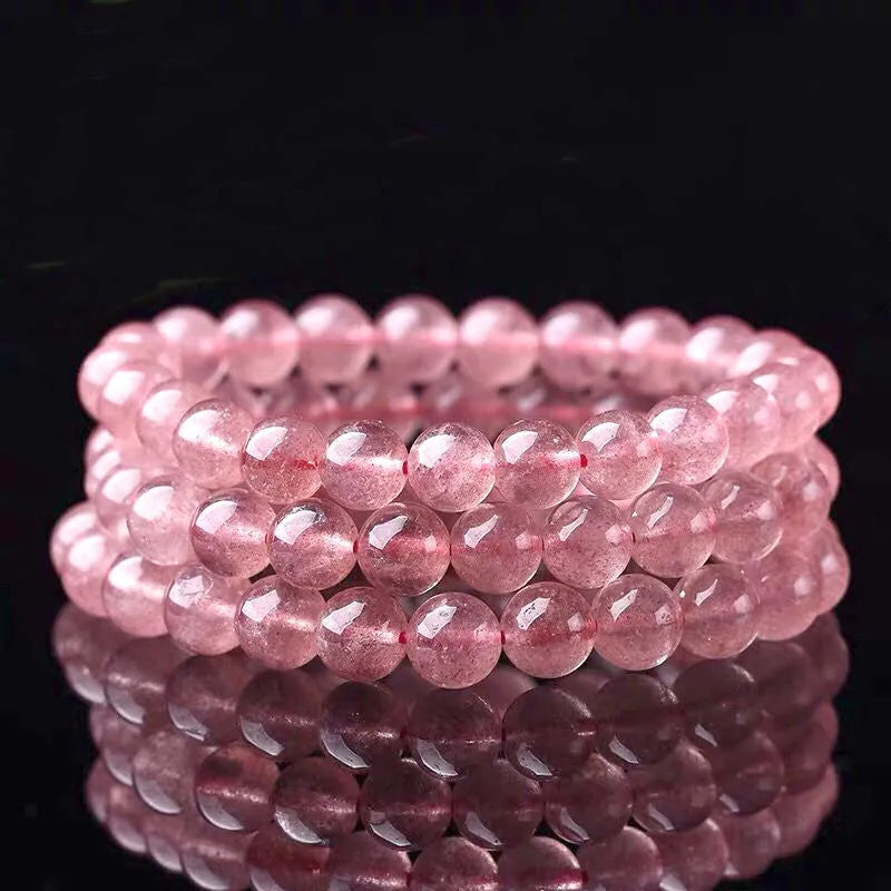 Women's strawberry quartz crystal bracelet in polished pink beads on a white background.