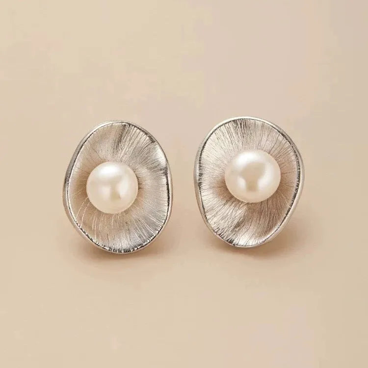 A pair of gold-coloured geometric sterling silver ear studs featuring a central pearl.