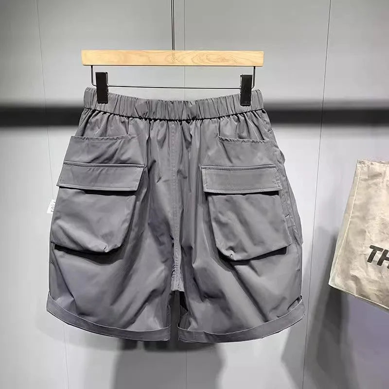Men's loose-fit black work shorts with pockets, shown on a model, above the knee length.