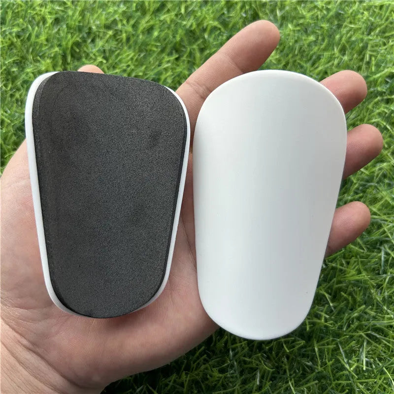 Extra small black and white plastic football shin guards for junior players.