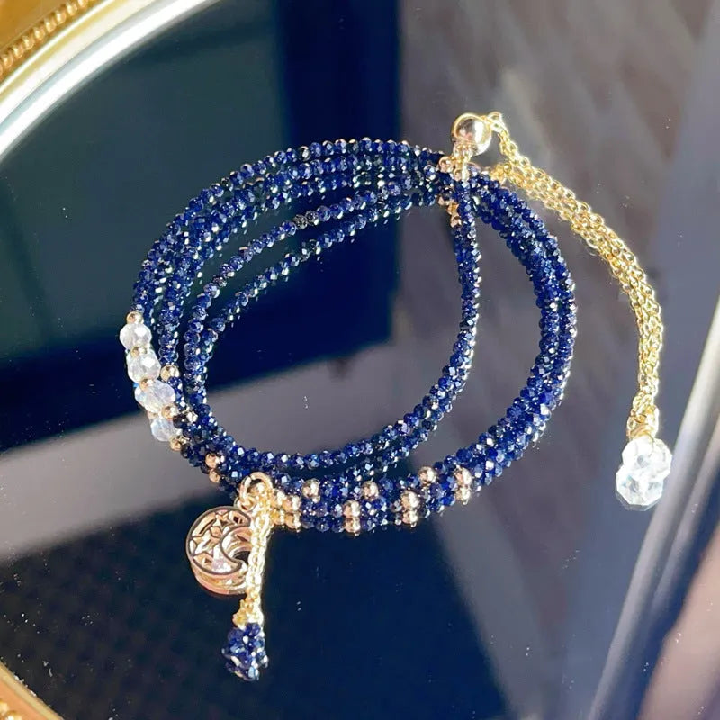Close-up of a women's multi-layer bracelet with three interlinked rings made from blue and gold cut sand stone.