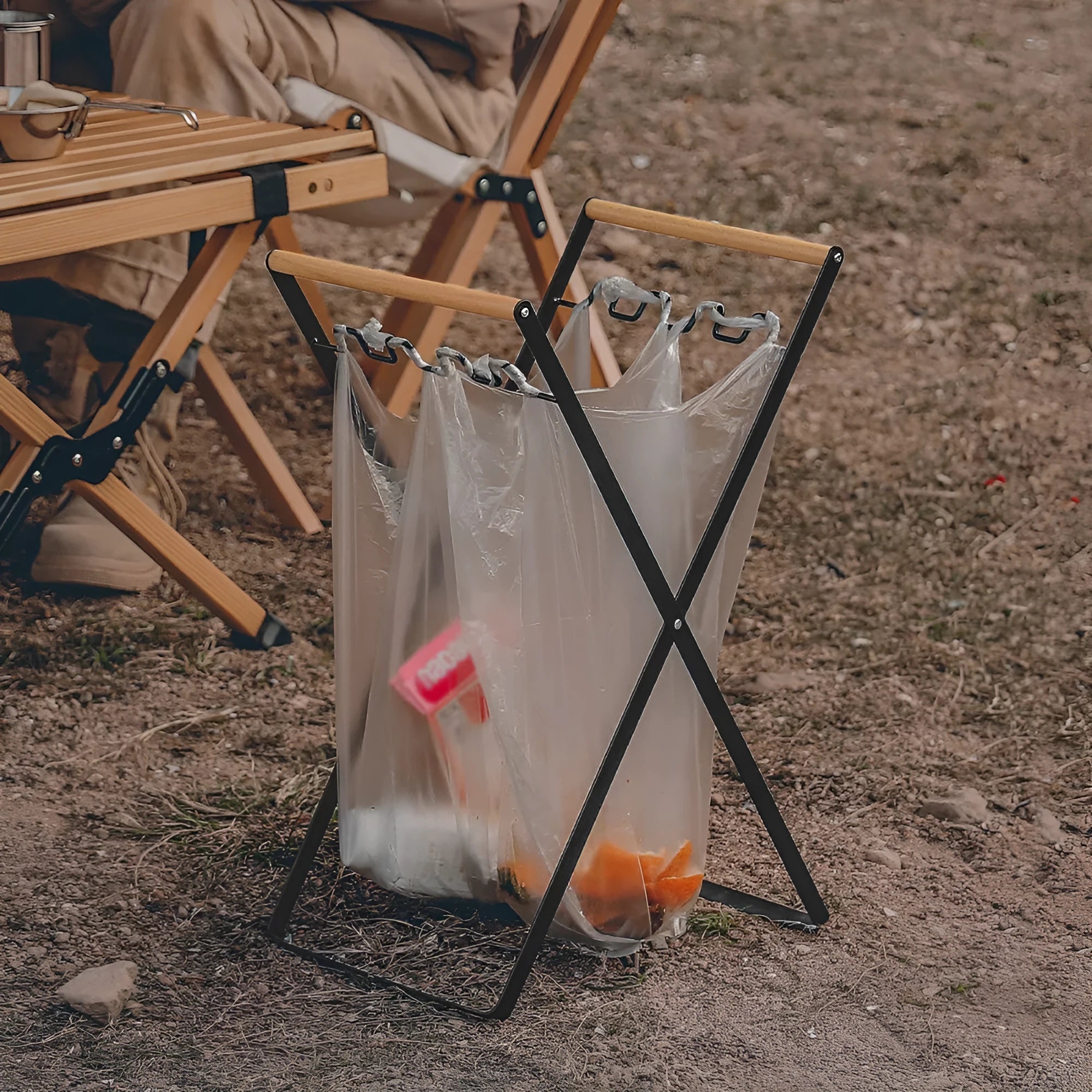 Black folding iron trash storage rack with a wooden handle holding a bin bag.