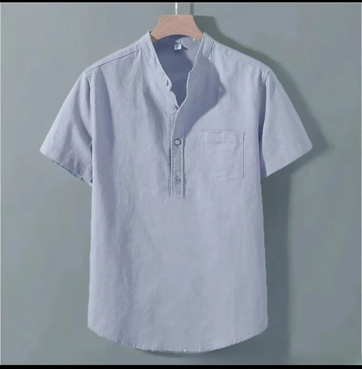 Man wearing a beige loose-fit short sleeve linen shirt with a stand collar.