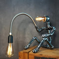 American retro industrial style water pipe table lamp with a dark iron shade on a wooden desk.
