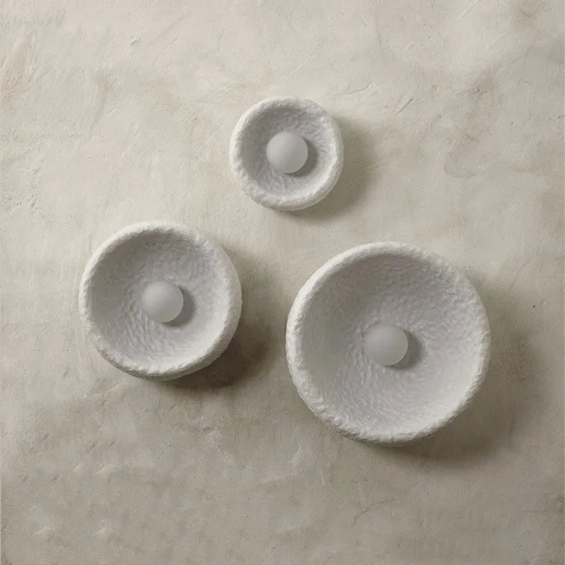 Japanese minimalist wall lamp with a round resin shade, shown in a modern room setting.