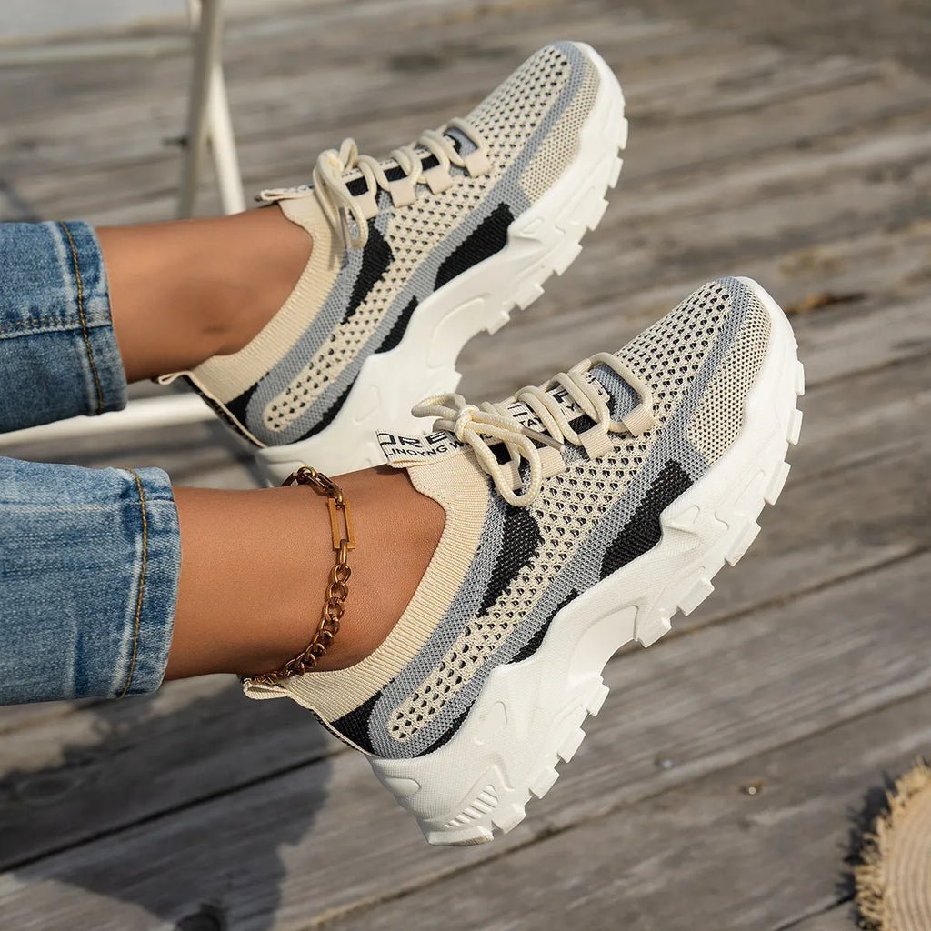 Women's Flyknit mesh lace-up sneakers in a grey colourway, showing the breathable upper and rubber sole.