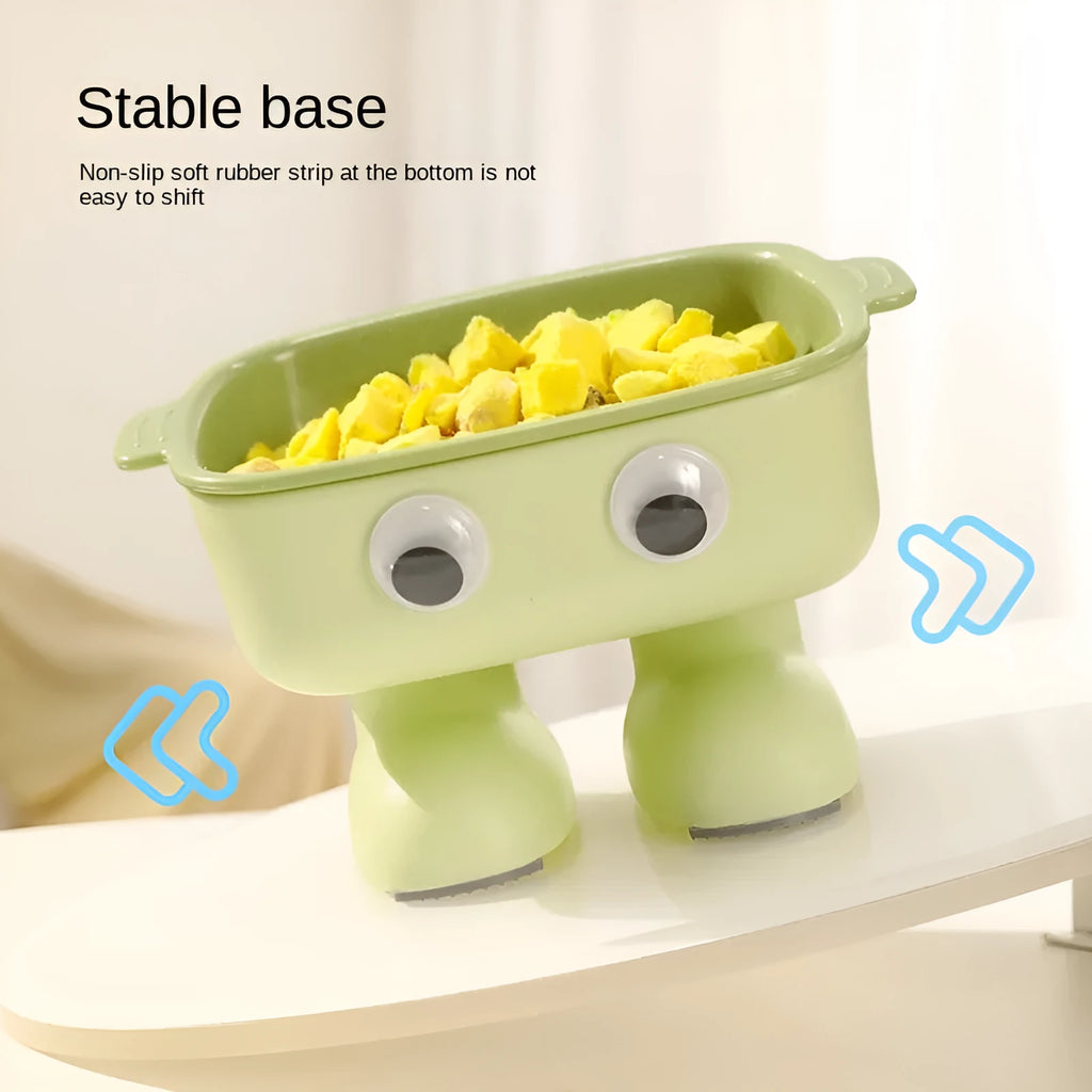 Green cartoon robot-shaped elevated cat bowl with tilted design and non-slip base on a table.