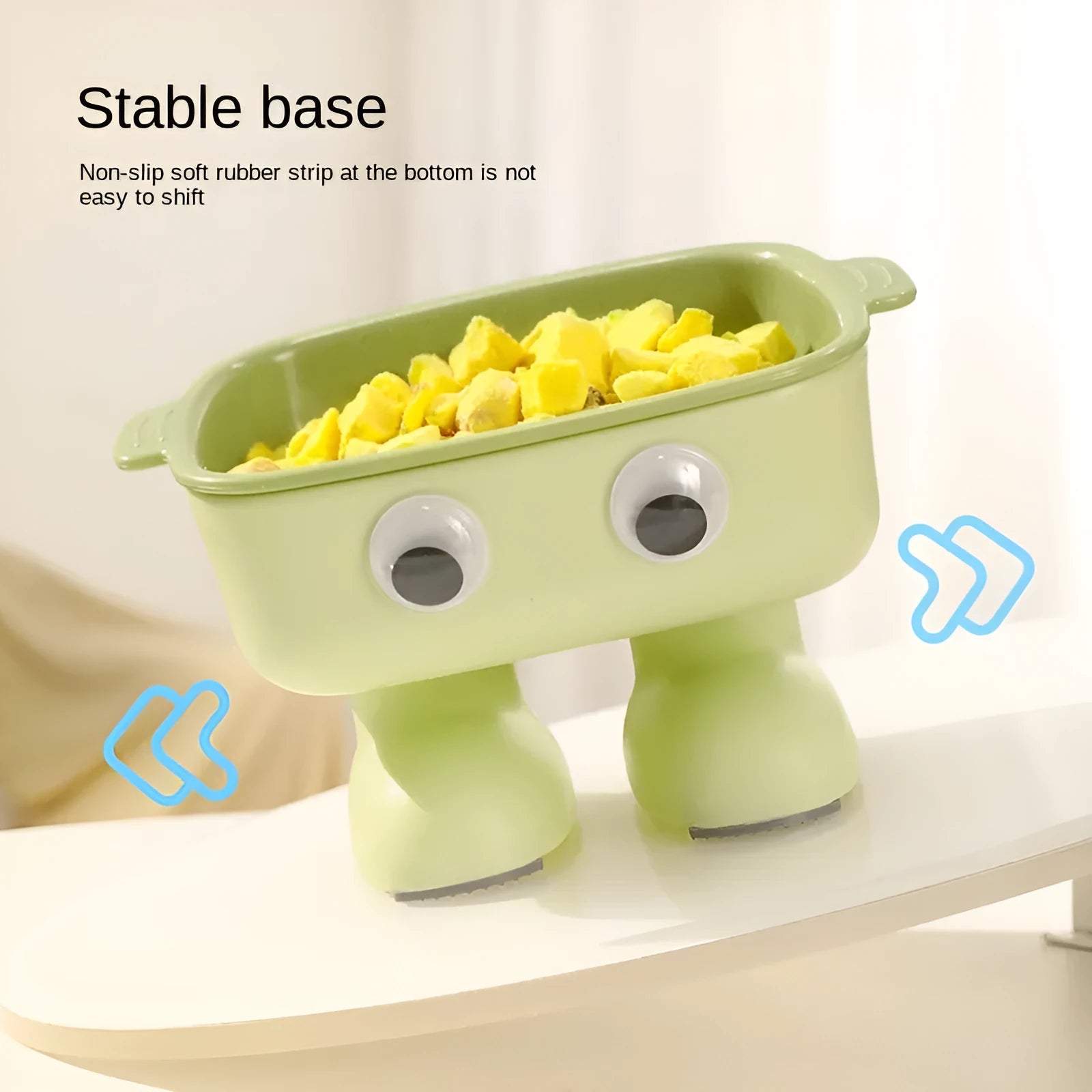 Green cartoon robot-shaped elevated cat bowl with tilted design and non-slip base on a table.