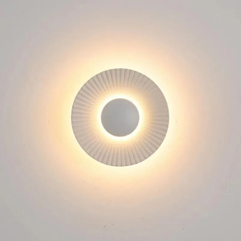 Round white and gold aluminium wall lamp mounted on a wall, LED light source visible.