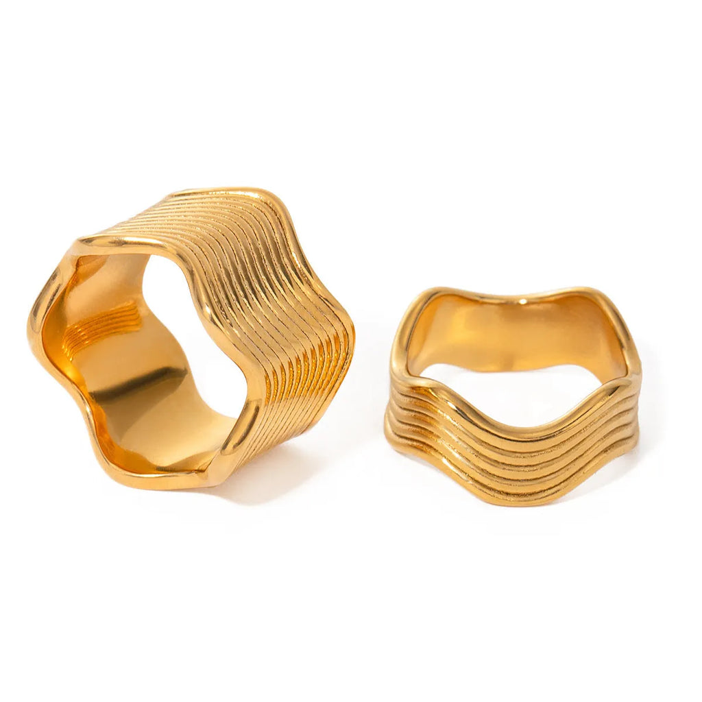Silver stainless steel wide band ring with a geometric wave pattern surface design.