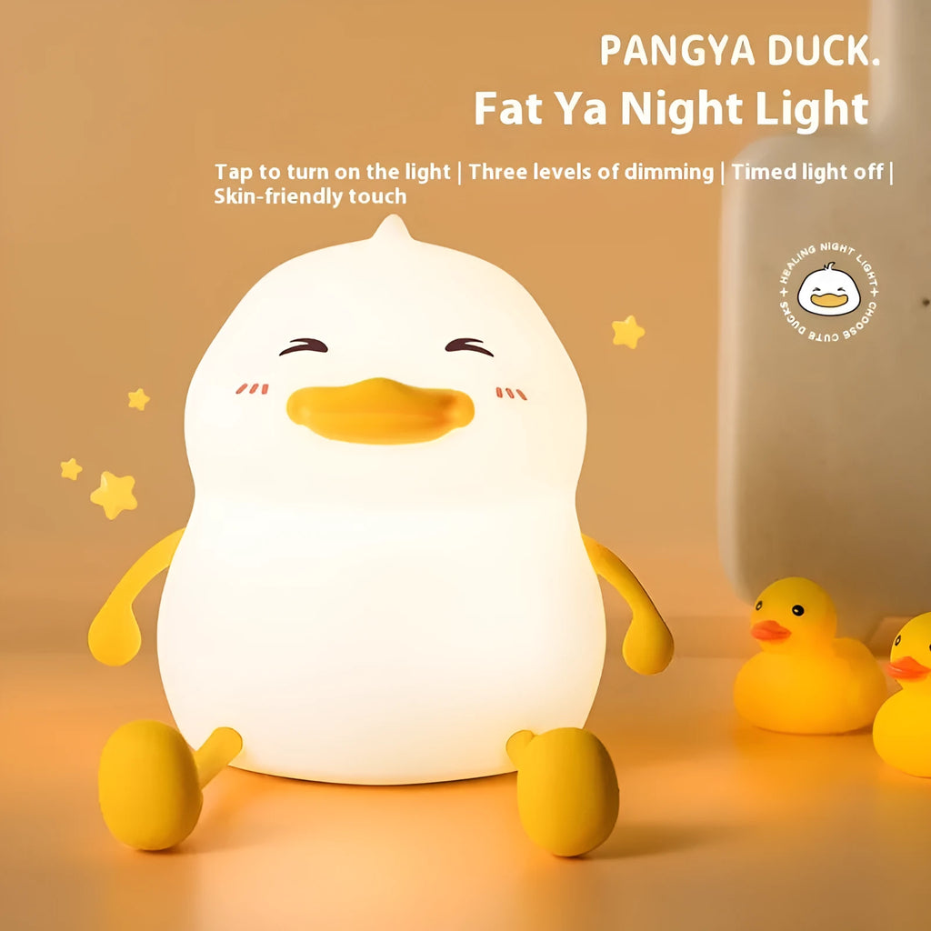 Chubby white silicone rechargeable night light on a wooden desk, showing phone holder function.