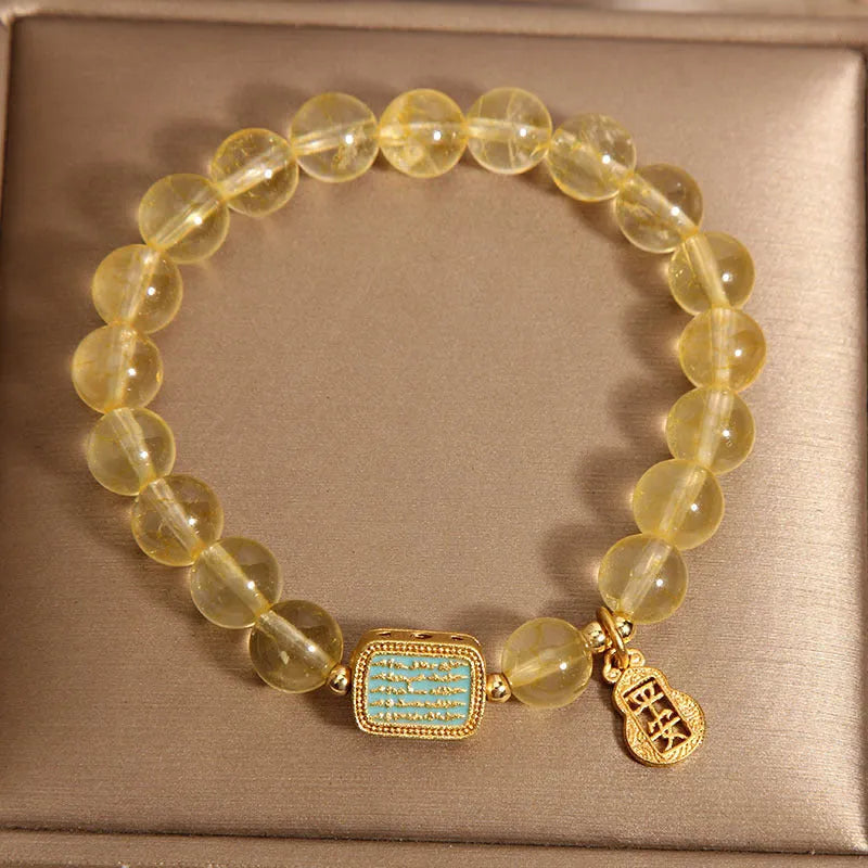 Women's yellow citrine crystal bracelet with sparkling rhinestone details on a white background.