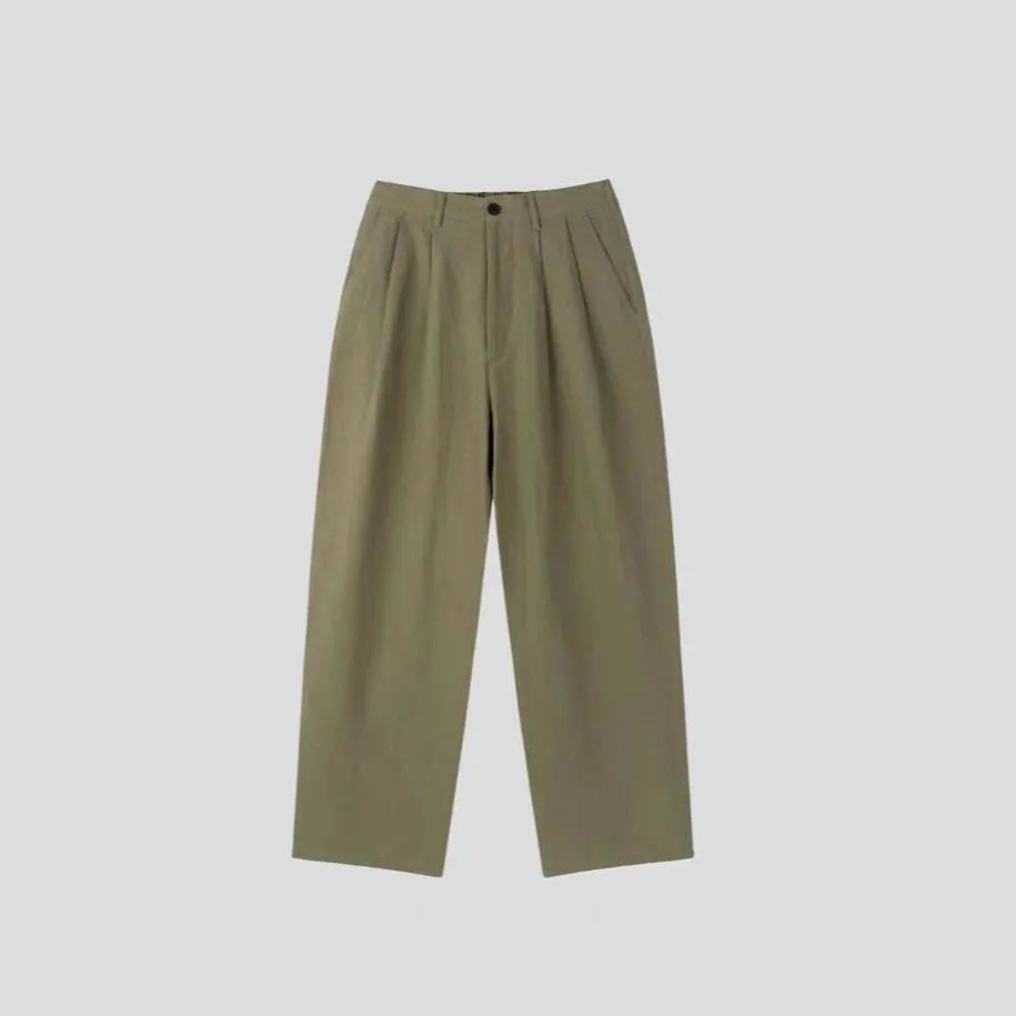 Man wearing apricot wide-leg cotton linen trousers with a mid waist and zip fly.