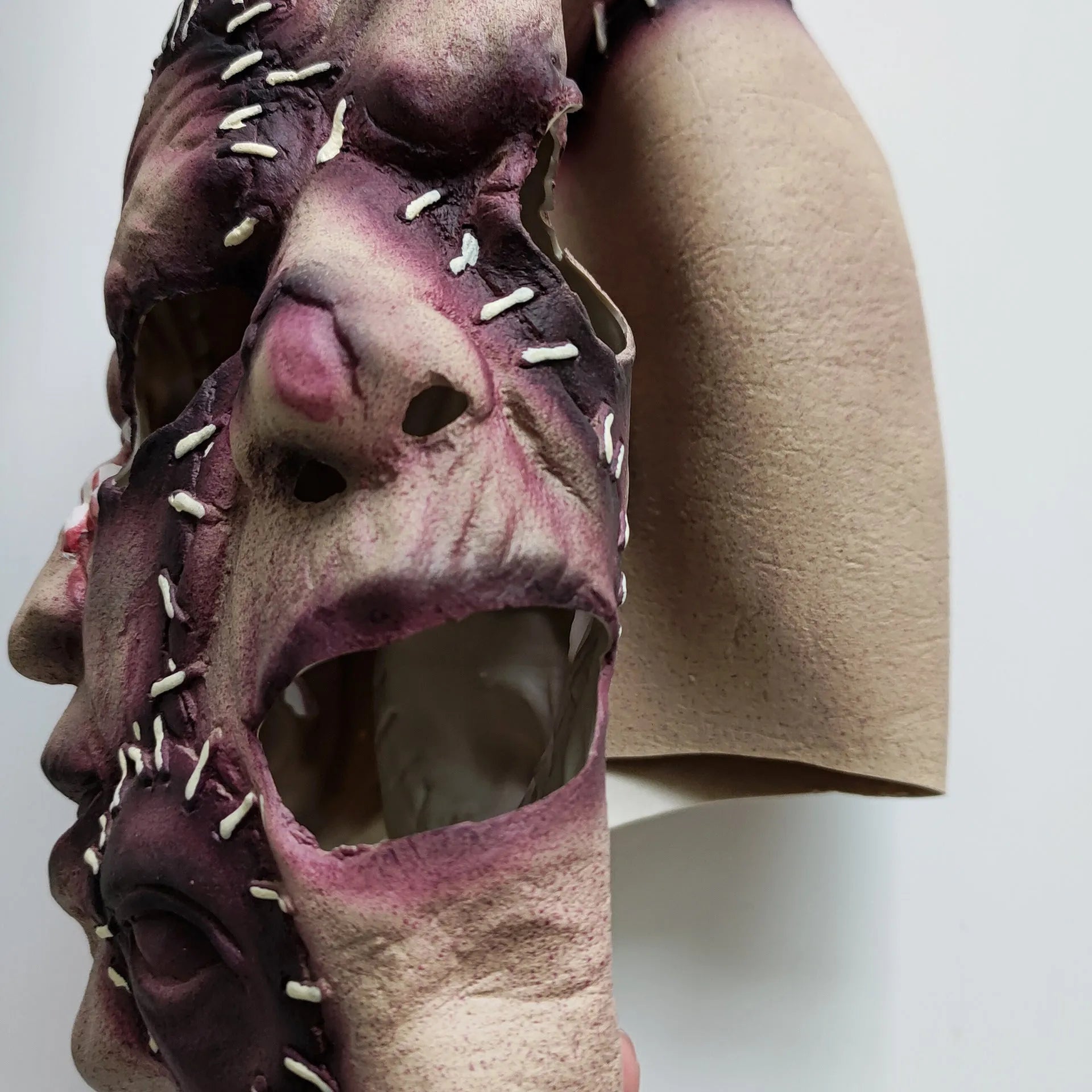 Three-sided grimace horror Halloween mask showing detailed latex texture and facial expression