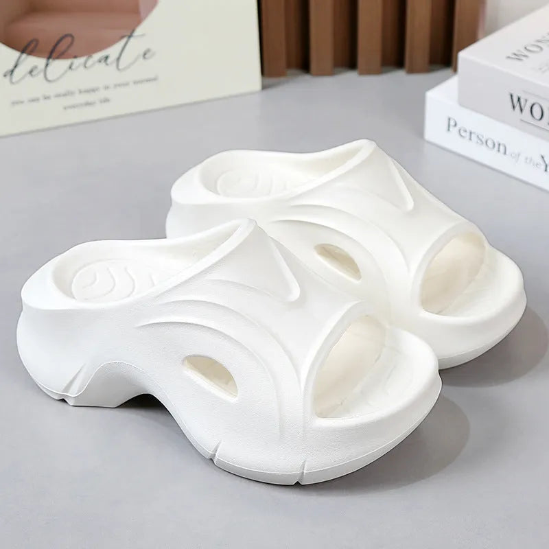 Women's white thick-soled EVA beach slippers with round toe on sand.