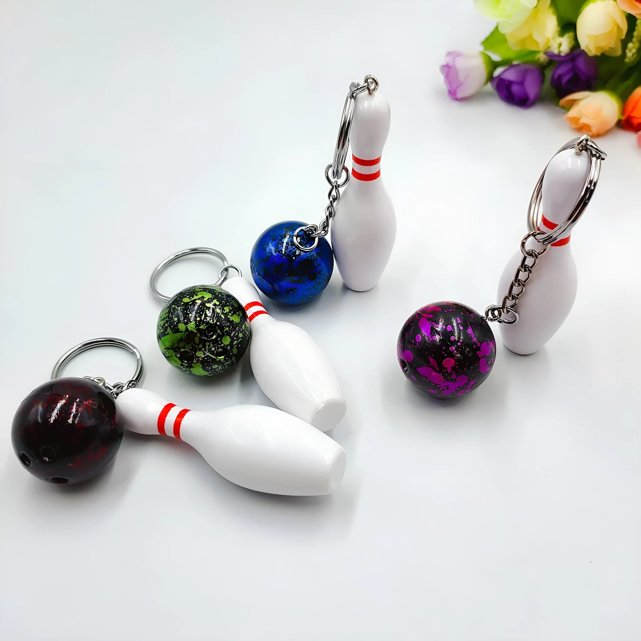 Miniature dark red bowling ball keychain on a metal ring with blue, purple, and green colour options shown
