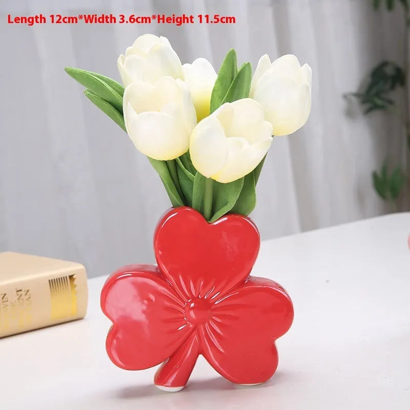 European style white porcelain ceramic vase in four colour options on a desktop.