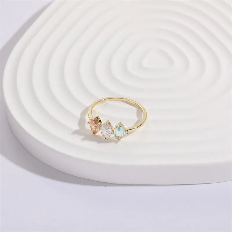 Women's gold-coloured ring with a horse eye design and three coloured zircon stones on a geometric band.