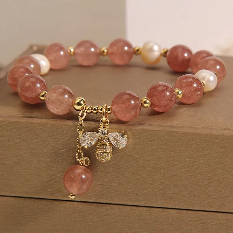 Women's adjustable bracelet with pink strawberry quartz stones, white freshwater pearls, and zircon accents on a wrist.