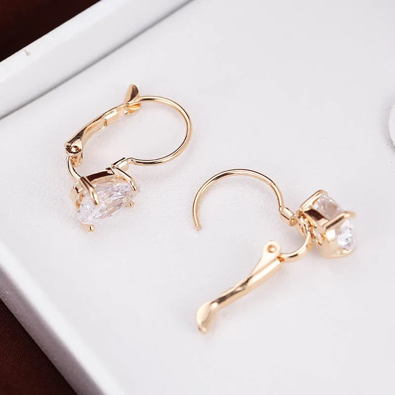 Drop-shaped women's fashion earrings in gold or platinum finish with an inlaid gem
