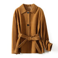 Women's belted caramel cashmere coat with leather stitching and a Peter Pan collar.