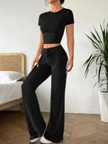 Women's black high waist trousers and short sleeve t-shirt co-ord set laid flat.