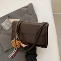 Brown structured women's PU shoulder bag with double straps, a pendant, and a horizontal square shape.