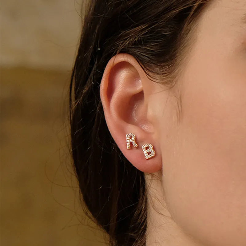 Gold plated alphabet letter earrings on a white background showing the full A-Z set with zircon detail.