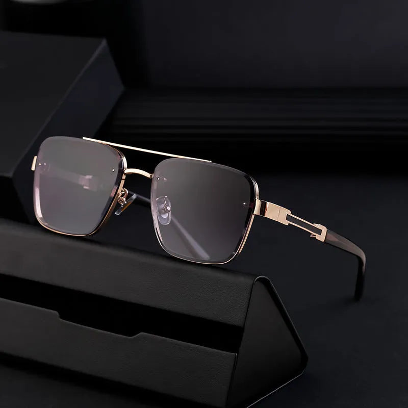 Men's vintage sunglasses with gold frame and grey lenses on a plain background.