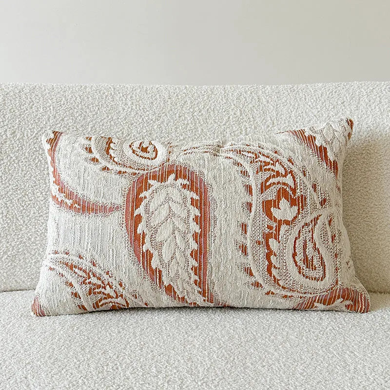 Jacquard woven paisley pattern pillow cover in amber colours on a sofa.