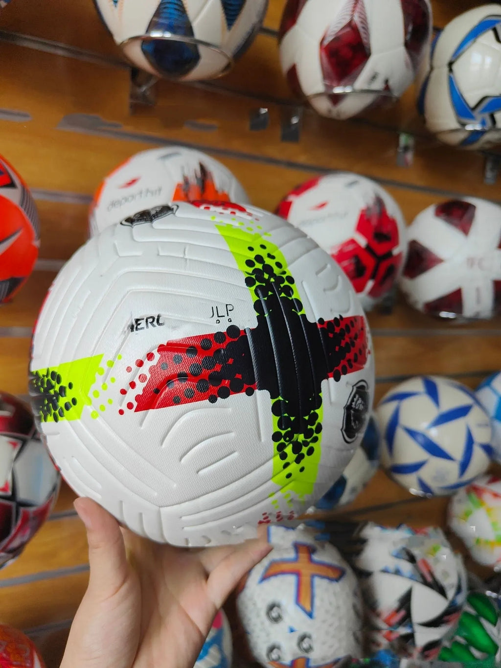 Fluorescent green official size 5 football with seamless thermal patch construction on a pitch.