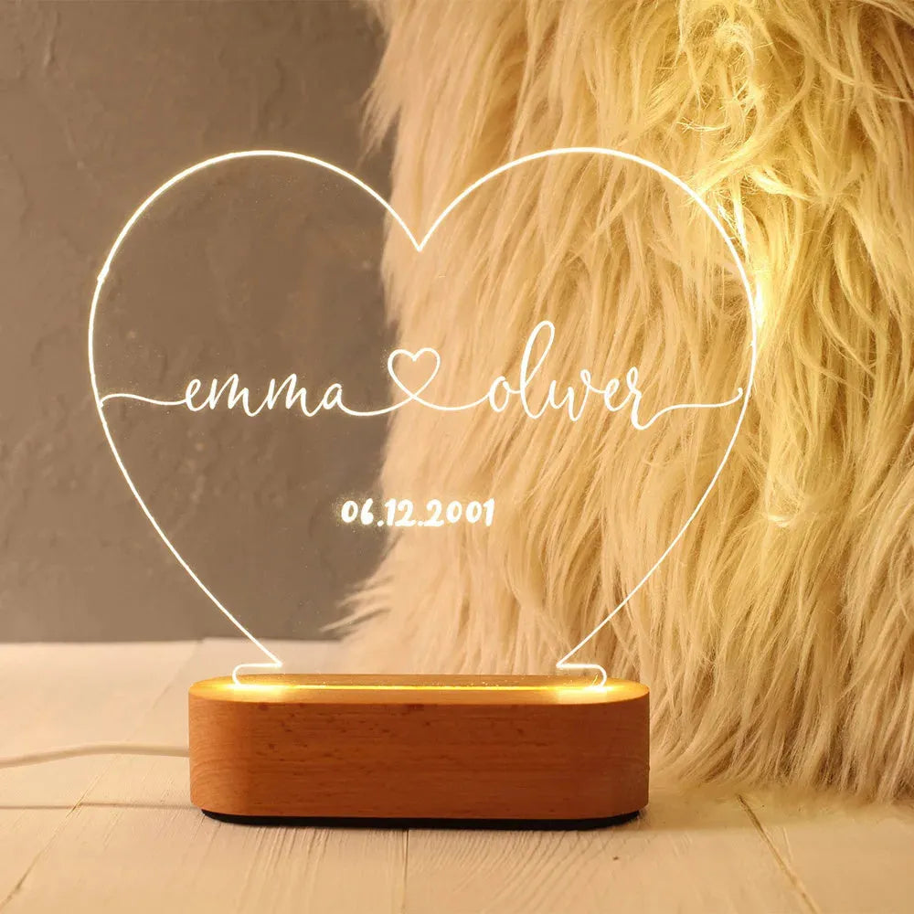 Custom acrylic night light with engraved names illuminated by LED base on bedside table
