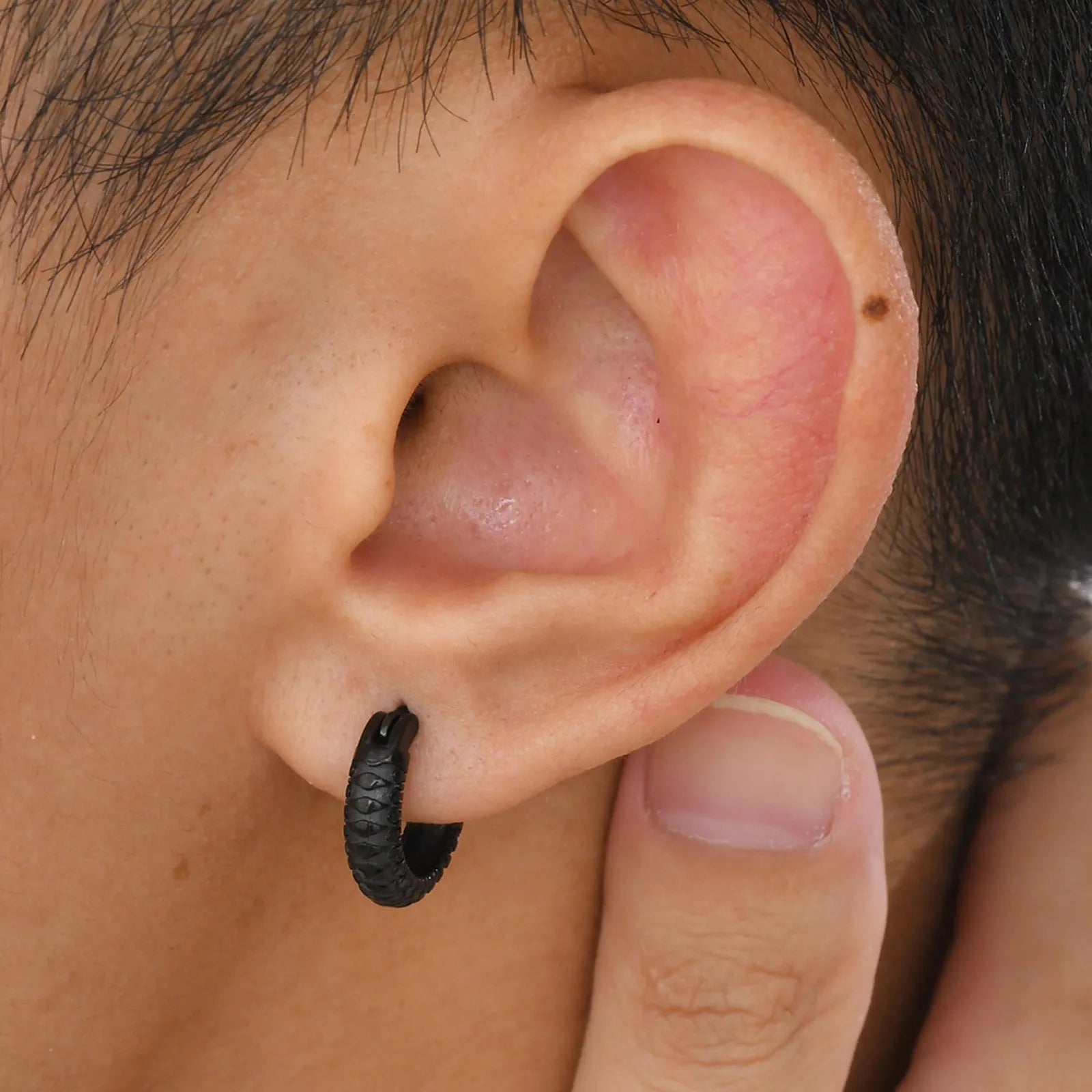 Close-up of a black stainless steel earring with a detailed snake pattern and hook fastening.