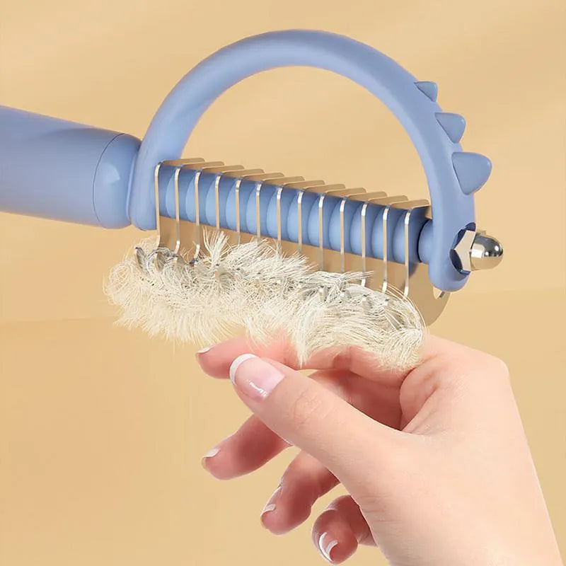 Blue dinosaur-shaped pet brush with a self-cleaning button and double-sided stainless steel bristles.