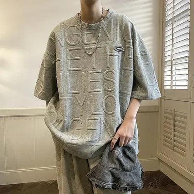 A grey men's loose-fit T-shirt with a retro style and raised 3D letter print on the chest.