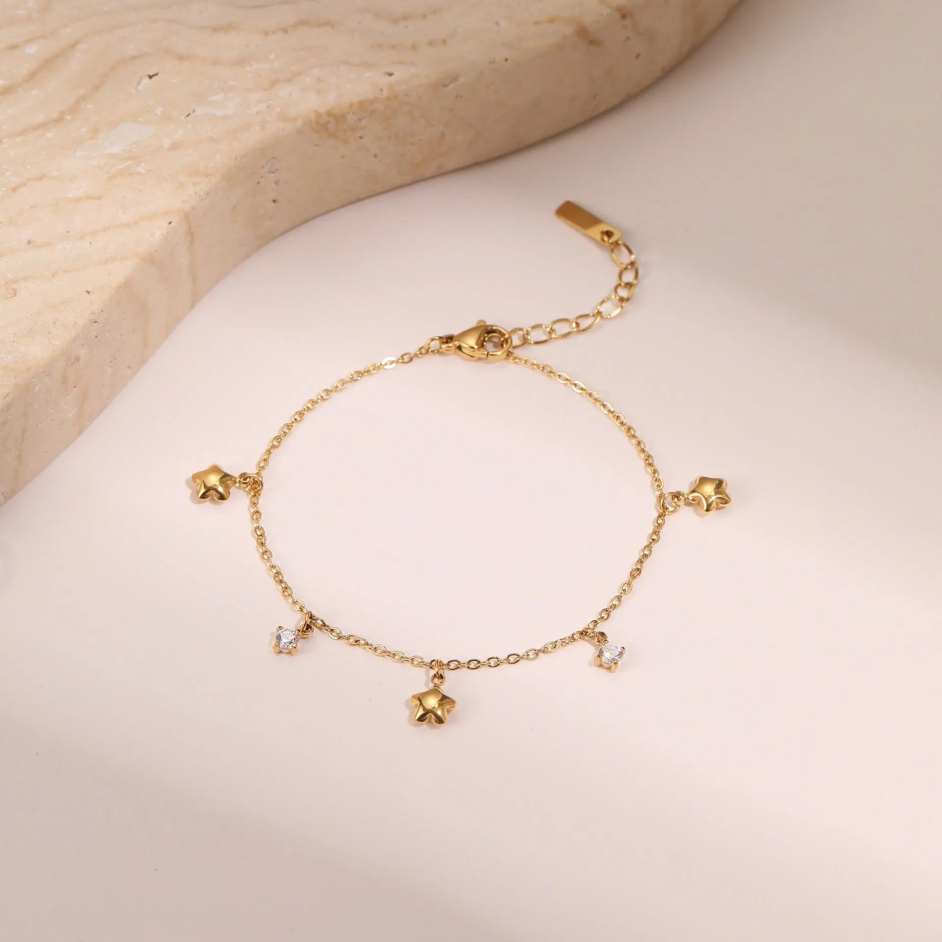 Gold electroplated stainless steel bracelet with a geometric star-shaped pendant.