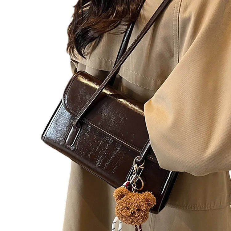Brown structured women's PU shoulder bag with double straps, a pendant, and a horizontal square shape.
