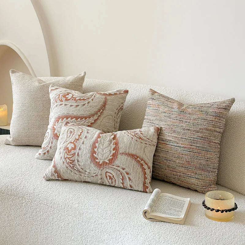 Jacquard woven paisley pattern pillow cover in amber colours on a sofa.