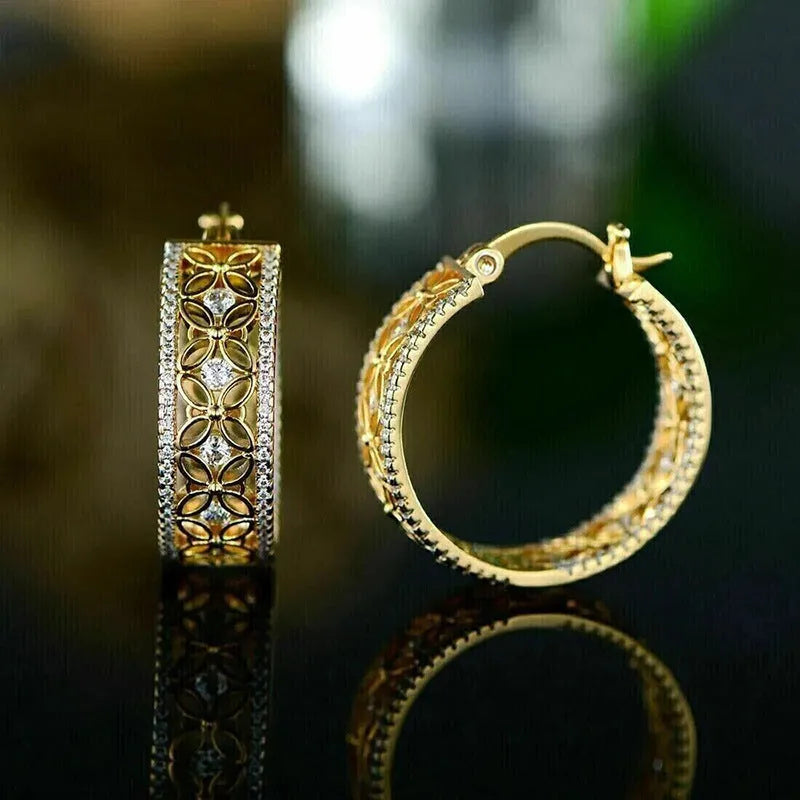 A pair of gold-coloured geometric clip-on earrings with horse, eye, flower and butterfly motifs on a copper base.
