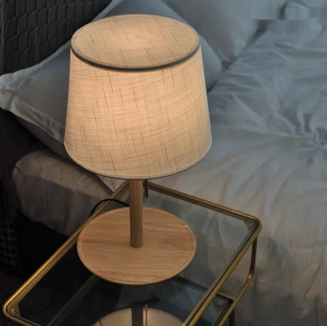 Walnut colour solid wood desk lamp with a white cloth shade and black cable switch.