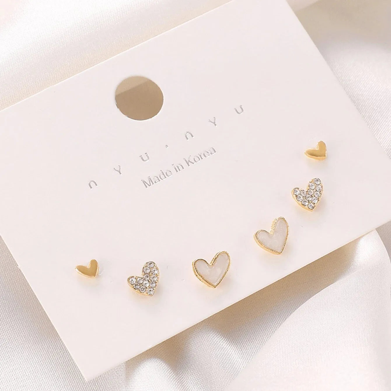 Three pairs of heart-shaped alloy earrings with electroplated finishes in gold, black, black-white, and pink colours
