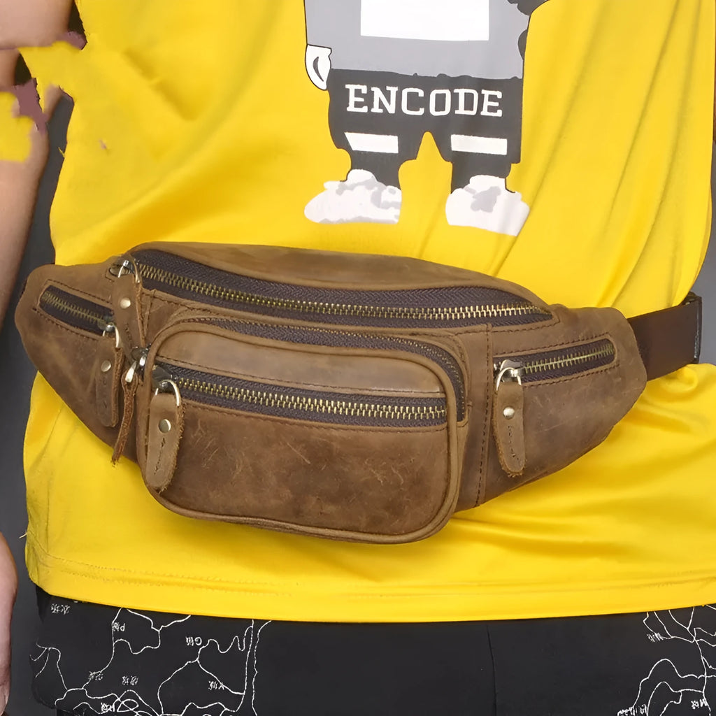 Brown leather messenger bag with a single shoulder strap shown open on a table