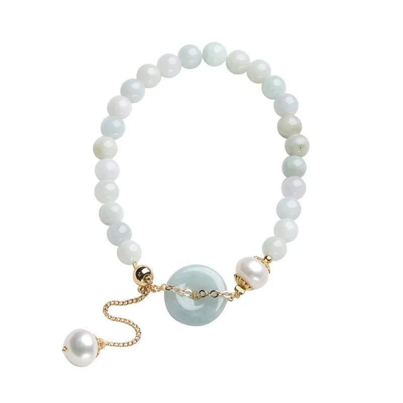 Close-up of a women's bracelet with a jade peace symbol buckle on a string of freshwater pearls.