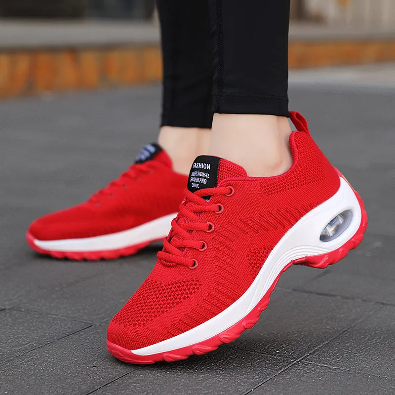 Red and black women's low-top mesh sneakers with front laces and a round toe, showing a mid-heel sole.