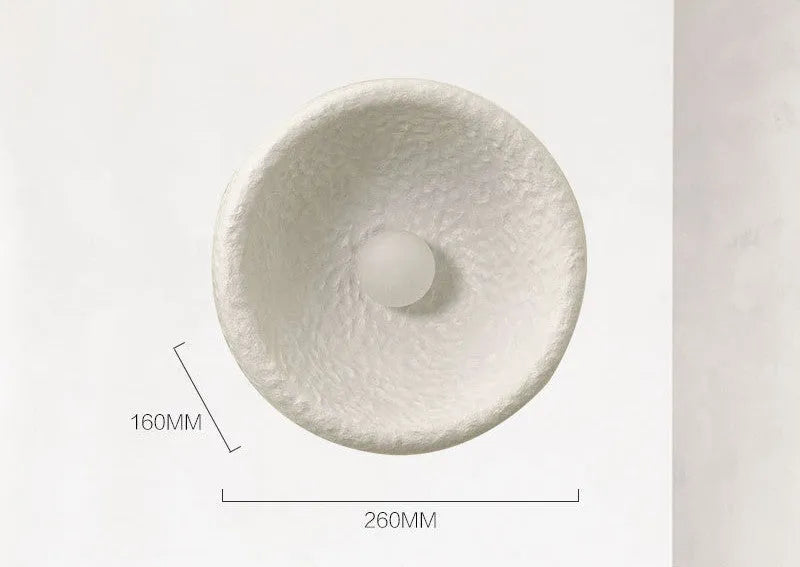 Japanese minimalist wall lamp with a round resin shade, shown in a modern room setting.