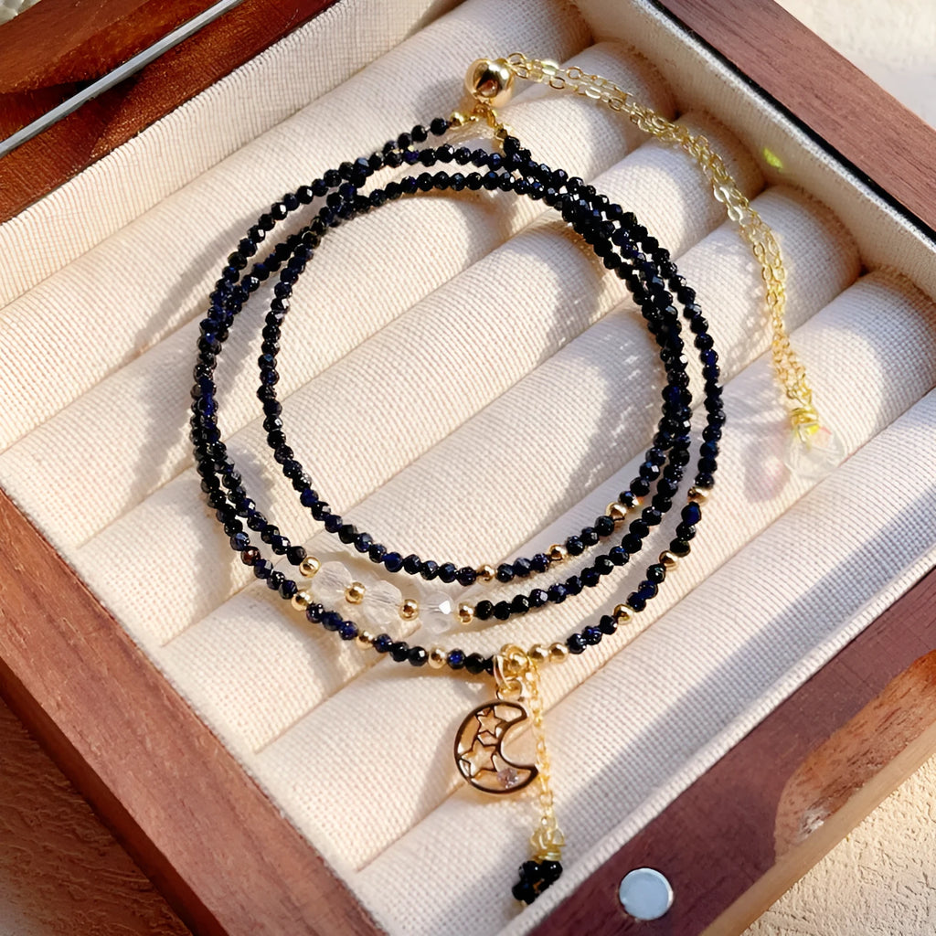 Close-up of a women's multi-layer bracelet with three interlinked rings made from blue and gold cut sand stone.