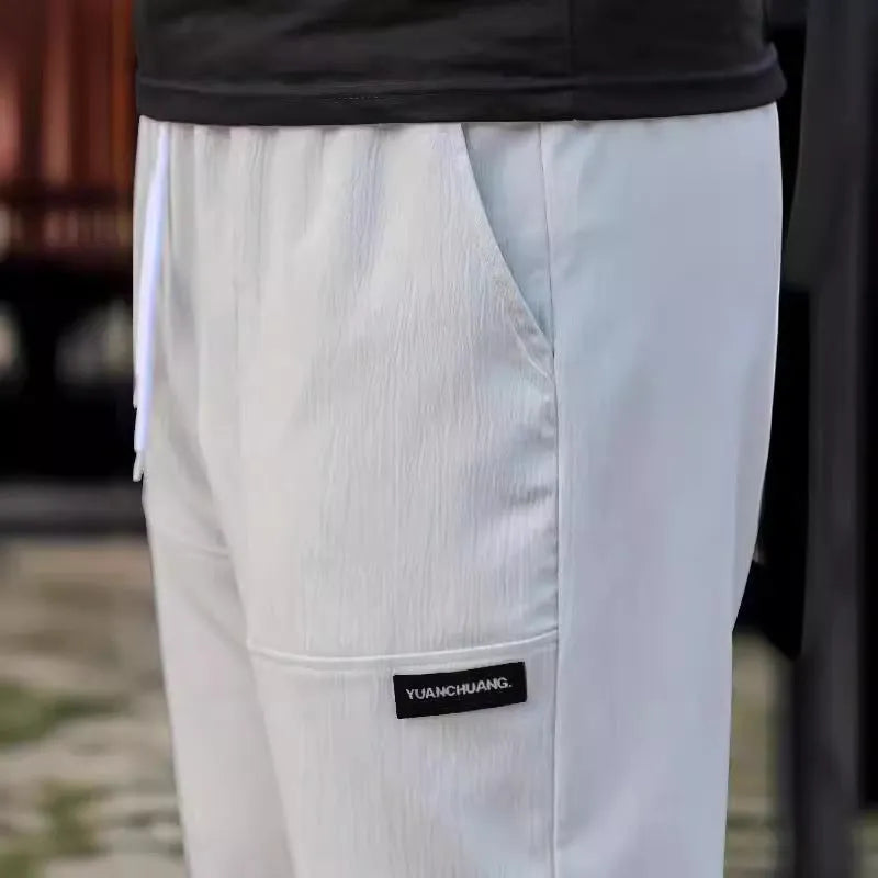 Men's polyester trousers for spring and autumn in various colours including light grey and dark green.