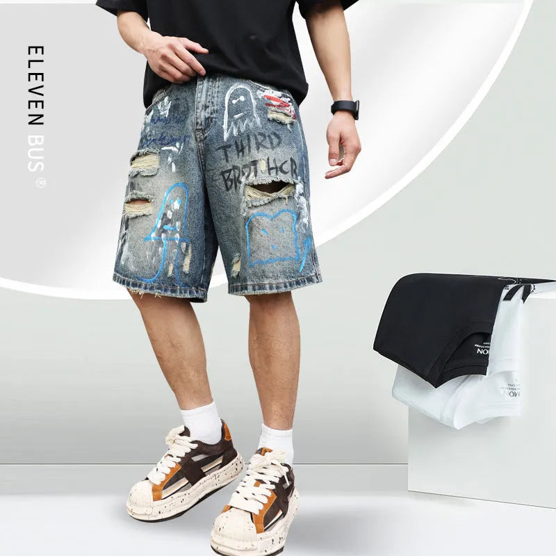 Blue men's denim jeans shorts with graffiti print and ripped details, showing straight leg and zipper fly.