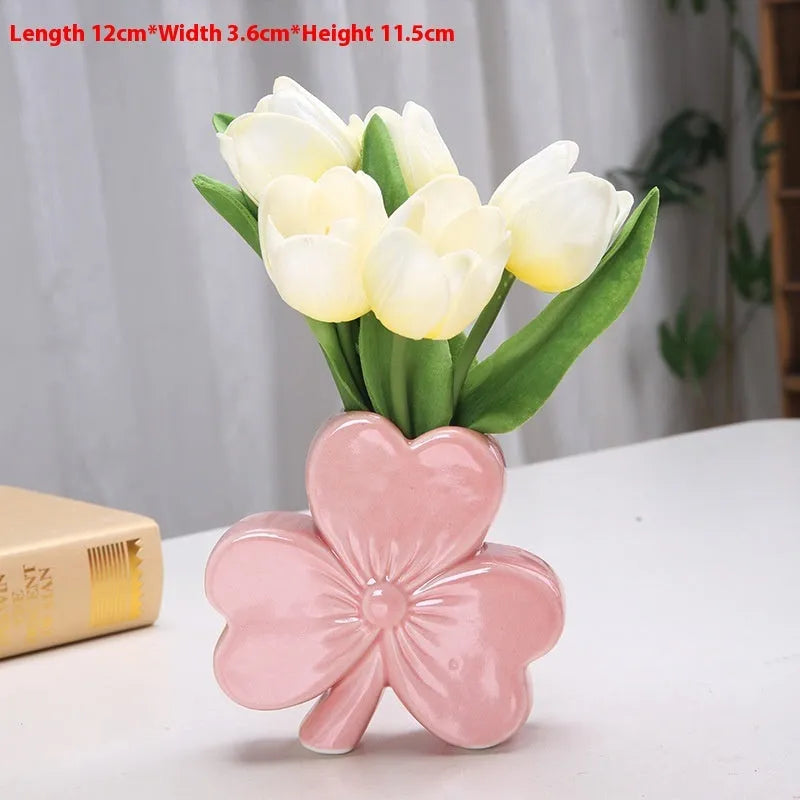 European style white porcelain ceramic vase in four colour options on a desktop.