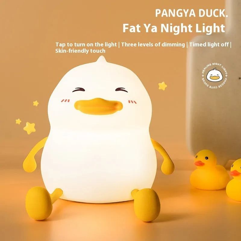 Chubby white silicone rechargeable night light on a wooden desk, showing phone holder function.